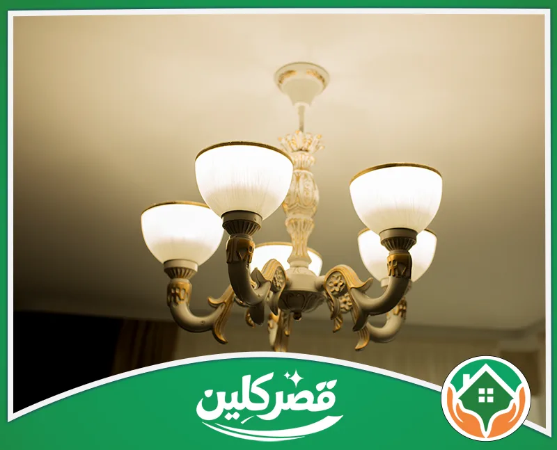 تنظيف ثريات كريستال بالرياض 0550575548 قصر كلين نجفة كلاسيكية أنيقة باللونين الأبيض والذهبي، مضاءة بنور دافئ يمنح المكان لمسة راقية وجذابة.