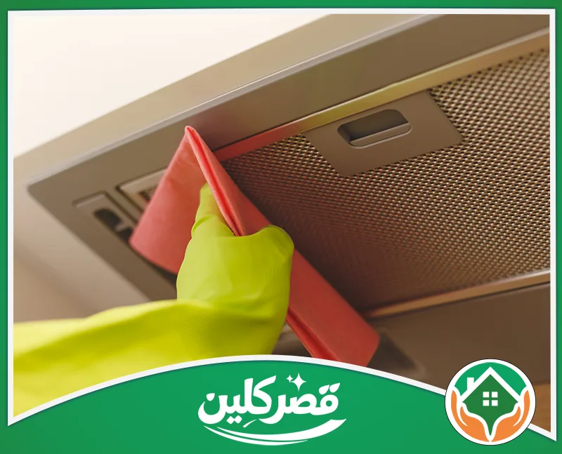 شركة تنظيف دكت مداخن المطاعم بالرياض 0550575548 قصر كلين مسح وتلميع الهيكل الخارجي لشفاط المطبخ المعدني باستخدام قطعة قماش وردية ويد ترتدي قفازاً أخضر لحمايتها.