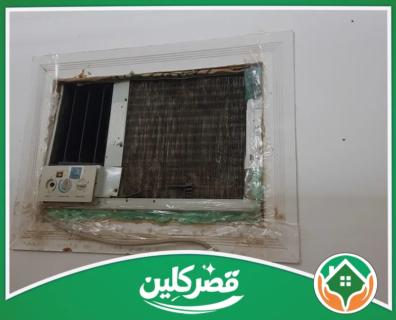 تنظيف مكيفات سبليت في الرياض 0550575548 قصر كلين مكيف هواء شباك قديم ومتهالك، مثبت في جدار أبيض ومحاط بشريط لاصق بلاستيكي وعازل تالف لحمايته.